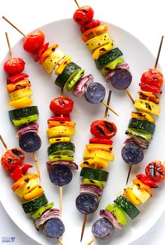 several skewers of vegetables are arranged on a white plate