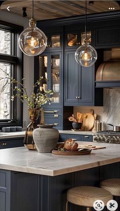 a kitchen island with stools and lights hanging from it's ceiling over the counter