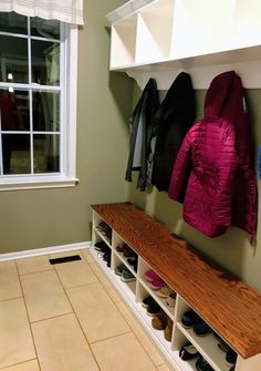 a coat rack with shoes and coats hanging on the wall next to a large window