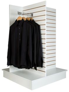 an open closet with three shirts hanging on hooks