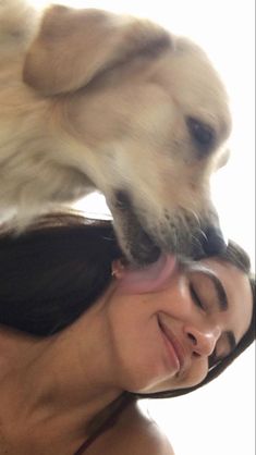 a woman with her head on the back of a dog's head, while it is being held up by its owner