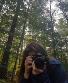 a woman taking a photo in the woods with her camera