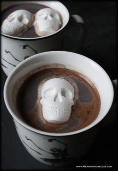 two mugs filled with hot chocolate and marshmallows in the shape of skulls