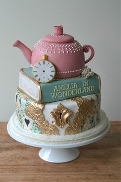 there is a cake that looks like a teapot on top of books and a clock