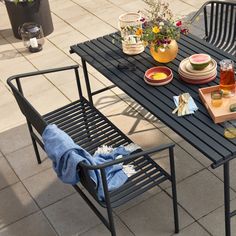 an outdoor table with plates and drinks on it, next to a potted plant