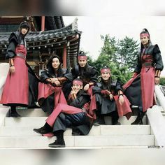 a group of people dressed in costumes posing for a photo on some steps with trees in the background