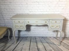 an antique white desk with gold handles and drawers