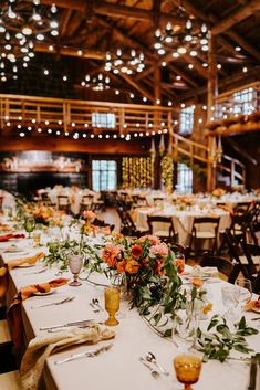 the tables are set with flowers and place settings for an elegant wedding reception at this rustic venue