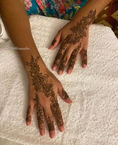 a woman's hands with henna tattoos on her left and right hand, sitting on a towel