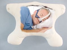 a man sleeping in a pillow with an oxygen mask on his face and eyes closed