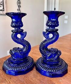 two blue glass candlesticks sitting on top of a wooden table