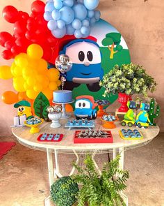 a table topped with balloons and toys next to a potted plant on top of a table