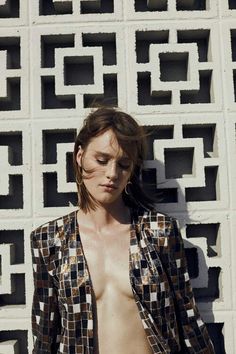 a shirtless woman standing in front of a white wall with geometric designs on it