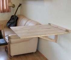 a living room with a couch, table and guitar hanging on the wall above it