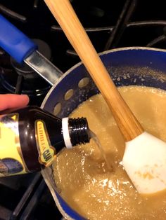 a person is stirring something in a pot on the stove with a wooden spatula