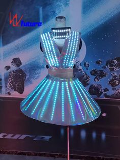 a light up dress on display in front of a wall with an advertisement behind it