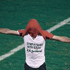 a man with his arms outstretched in the air on a tennis court while wearing a red hoodie and black shorts