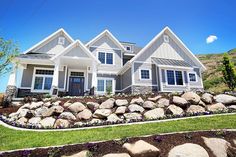 a large house with lots of rocks in the front yard and landscaping on the side