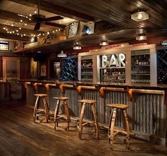 a bar with three wooden stools in front of it and lights on the ceiling