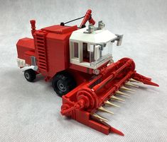 a red and white toy tractor with spikes attached to it