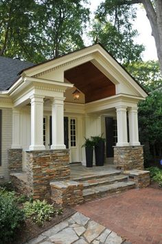 an image of a small house with stone steps and porches on the front yard