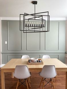 a dining room table with four chairs and a light fixture hanging from it's ceiling