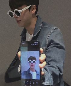 a man wearing sunglasses holding up a cell phone