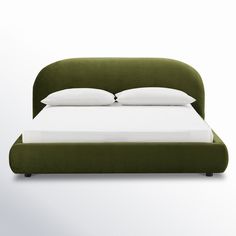 a bed with white pillows and green headboard on top of it, in front of a white wall