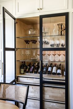 an open cabinet with wine glasses and bottles