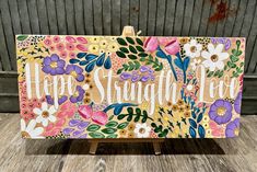 an easel with flowers painted on it and the words happy, straight - faced