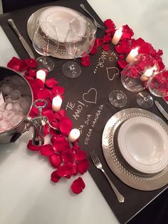 a table set for valentine's day with candles and rose petals