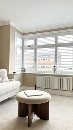 a living room filled with furniture and a large window covered in shuttered shades on the windowsill