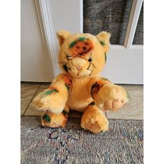 a stuffed animal sitting on the floor next to an open door with it's eyes painted orange and green