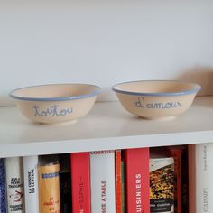 two bowls sitting on top of a book shelf next to each other in front of books