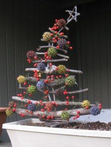 a christmas tree made out of branches and berries in a bathtub next to a potted plant