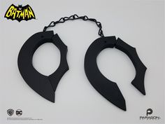 two black metal handcuffs with chains attached to them, one is shaped like a bat