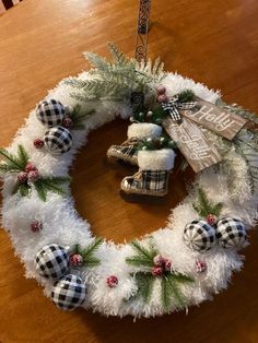 a christmas wreath made out of white fluffy yarn and plaid ornaments on a wooden table