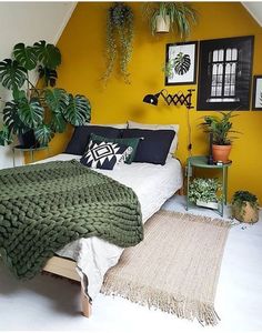 a bedroom with yellow walls and green plants on the wall above the bed, along with an area rug