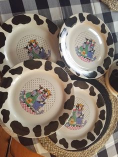 four plates with cartoon characters on them sitting on a checkered tablecloth covered placemat