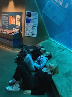 two people laying on the ground in front of an aquarium