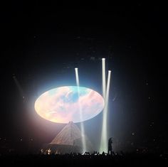 the stage is lit up with bright lights and some people are standing in front of it