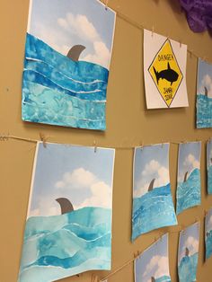 some pictures are hanging on the wall and there is a shark in the water with a yellow sign