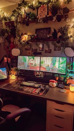 two computer monitors sitting on top of a desk in front of a wall with plants