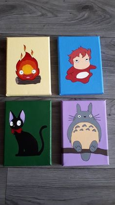 four different colored canvases with cartoon characters painted on them, sitting on a wood floor