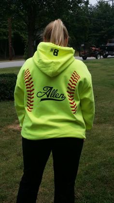 a woman wearing a neon green hoodie with softballs on it