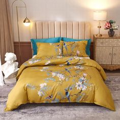 a bed with yellow and blue comforters on top of it in a room next to two lamps