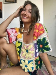 a woman is sitting on the floor with her hand in her hair and smiling at the camera