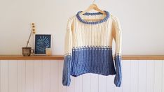 a blue and white sweater hanging on a wooden shelf