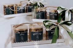 two clear boxes filled with jams on top of a white table covered in green ribbon