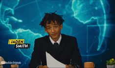 a man sitting at a table in front of a blue screen with the words jaden smith on it